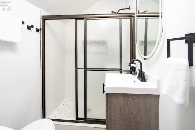 bathroom featuring vanity, a shower with shower door, and toilet