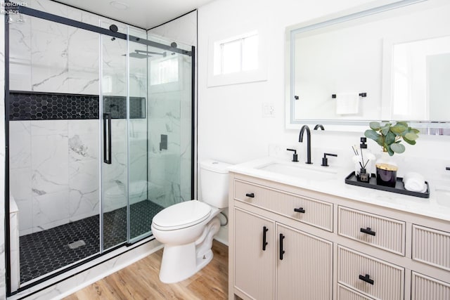 bathroom with hardwood / wood-style flooring, vanity, toilet, and a shower with door