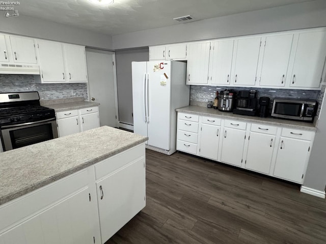 kitchen featuring a baseboard radiator, white cabinets, dark hardwood / wood-style flooring, decorative backsplash, and stainless steel appliances