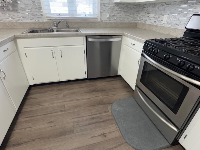 kitchen with appliances with stainless steel finishes, dark hardwood / wood-style floors, sink, and white cabinets