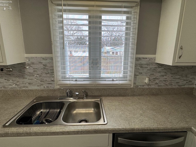 kitchen featuring white cabinetry, dishwashing machine, and sink