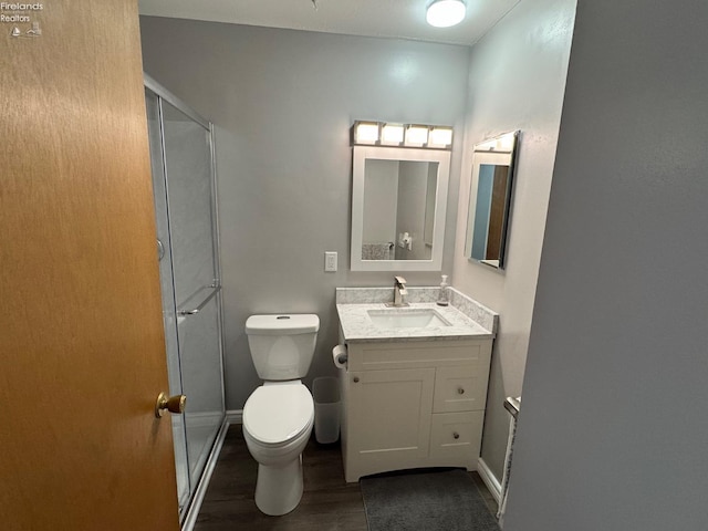 bathroom featuring vanity, wood-type flooring, a shower with door, and toilet