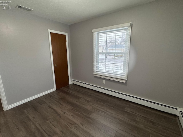 unfurnished room featuring baseboard heating, dark hardwood / wood-style flooring, and a textured ceiling