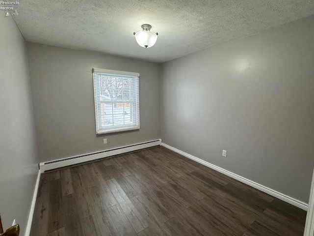 spare room featuring a baseboard heating unit, dark hardwood / wood-style floors, and a textured ceiling