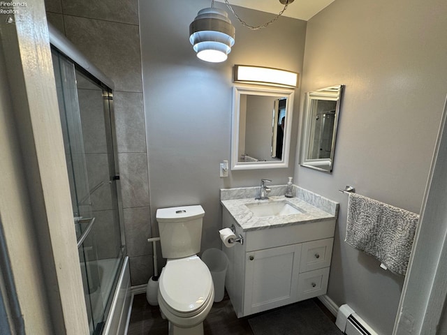 full bathroom featuring vanity, a baseboard heating unit, combined bath / shower with glass door, and toilet