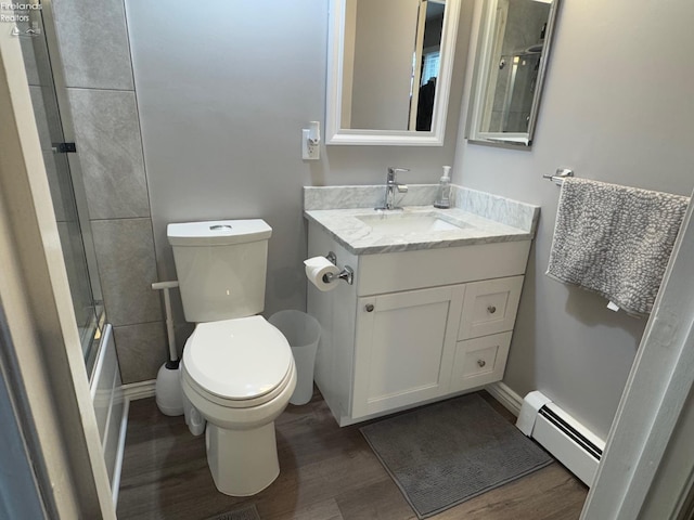 full bathroom with hardwood / wood-style flooring, enclosed tub / shower combo, baseboard heating, vanity, and toilet