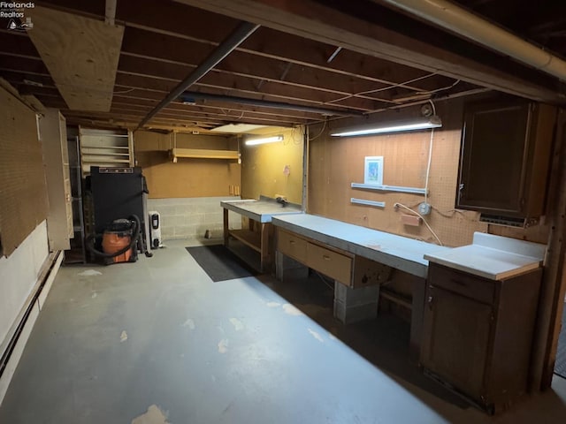 basement featuring a baseboard heating unit and a workshop area