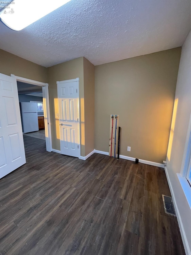 empty room with dark wood-type flooring and a textured ceiling