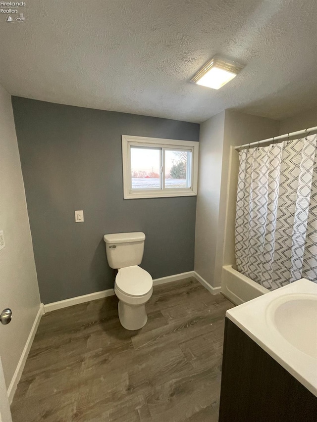 full bathroom with toilet, a textured ceiling, vanity, shower / bath combo with shower curtain, and hardwood / wood-style floors