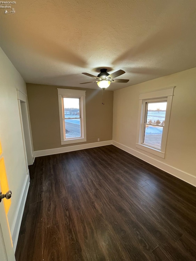 spare room featuring ceiling fan, dark wood-type flooring, and a textured ceiling