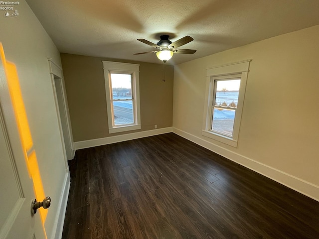 unfurnished bedroom with multiple windows, ceiling fan, dark hardwood / wood-style floors, and a textured ceiling