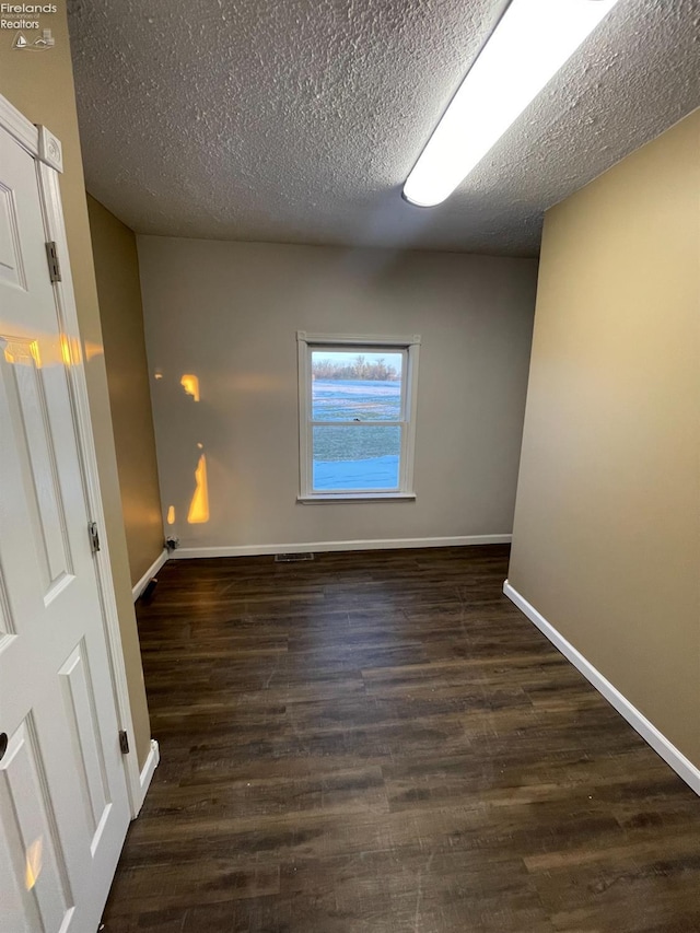 unfurnished room featuring dark wood-type flooring and a textured ceiling