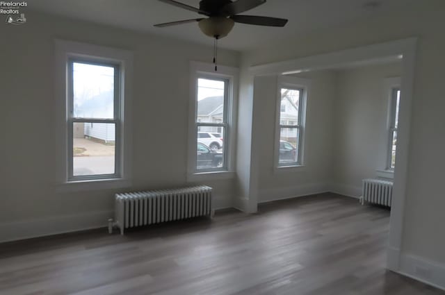 spare room with hardwood / wood-style flooring, radiator heating unit, and plenty of natural light