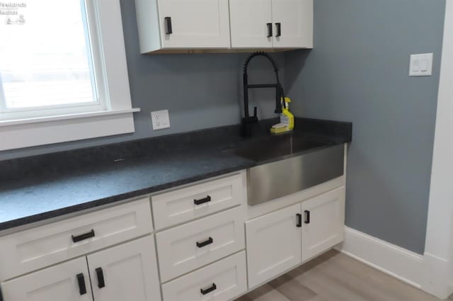 kitchen with sink, white cabinets, and light wood-type flooring