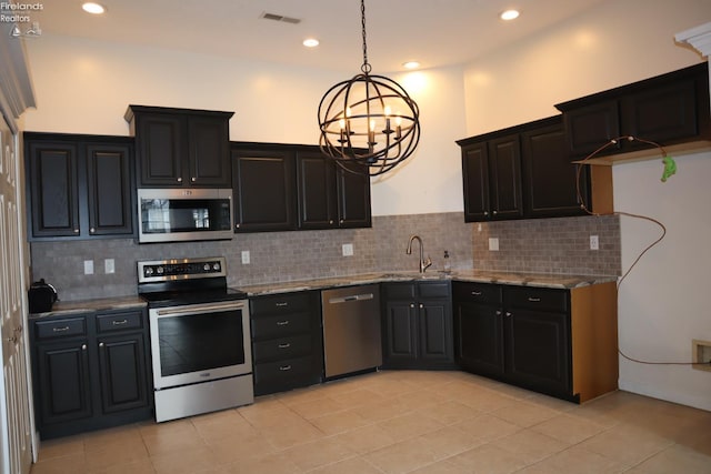 kitchen with pendant lighting, sink, decorative backsplash, light stone counters, and stainless steel appliances