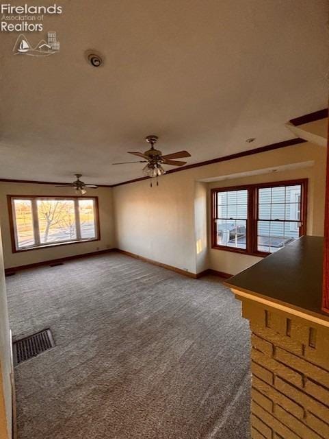 unfurnished living room with crown molding, ceiling fan, and carpet floors