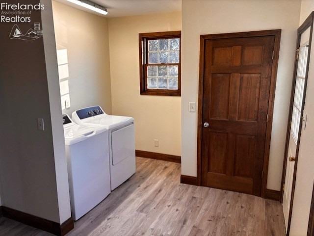 laundry room with washing machine and clothes dryer and light hardwood / wood-style floors