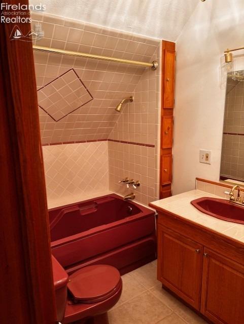 full bathroom with tiled shower / bath, toilet, tile patterned floors, and vanity