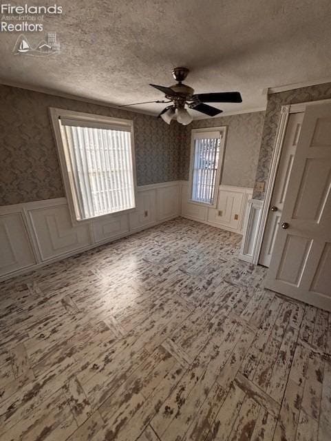 spare room featuring ceiling fan, crown molding, and a textured ceiling