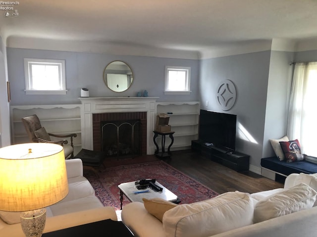 living room featuring a brick fireplace and dark hardwood / wood-style flooring