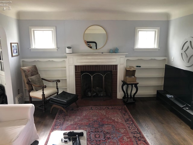 sitting room with a fireplace, a healthy amount of sunlight, and dark hardwood / wood-style floors