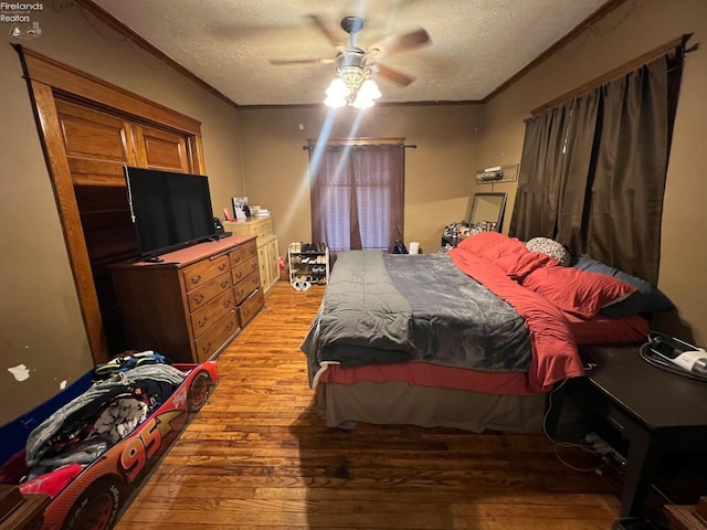 bedroom featuring ornamental molding, ceiling fan, a textured ceiling, and light hardwood / wood-style floors