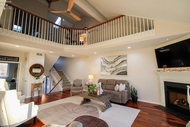 living room featuring a towering ceiling, dark hardwood / wood-style floors, and ceiling fan