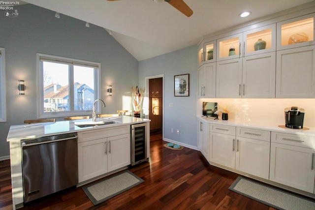 kitchen featuring lofted ceiling, sink, white cabinets, stainless steel dishwasher, and beverage cooler