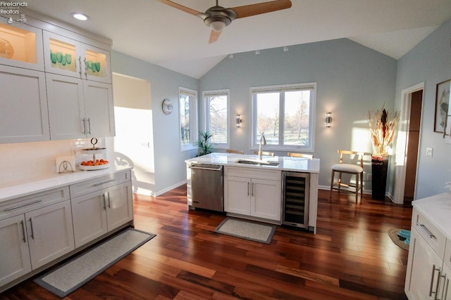 kitchen featuring vaulted ceiling, white cabinetry, sink, beverage cooler, and stainless steel dishwasher