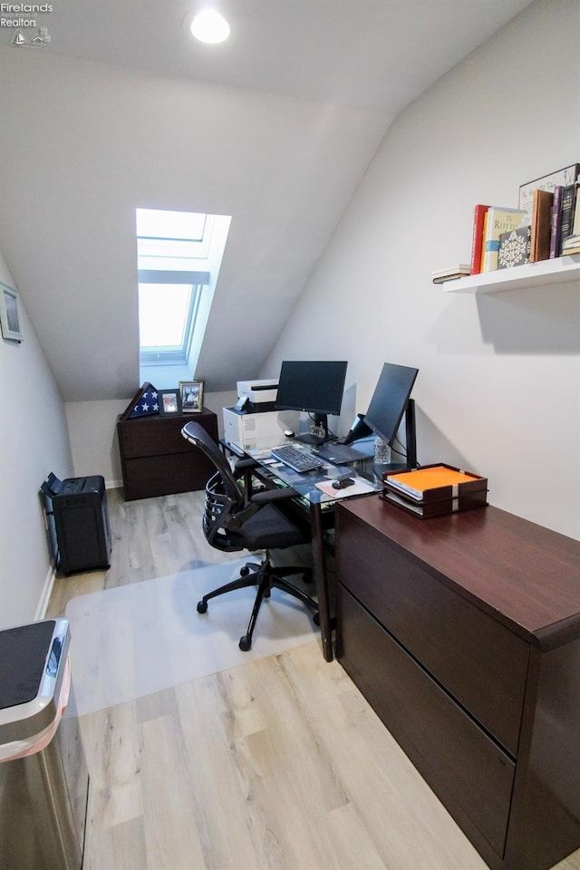 office space with lofted ceiling with skylight and light hardwood / wood-style floors