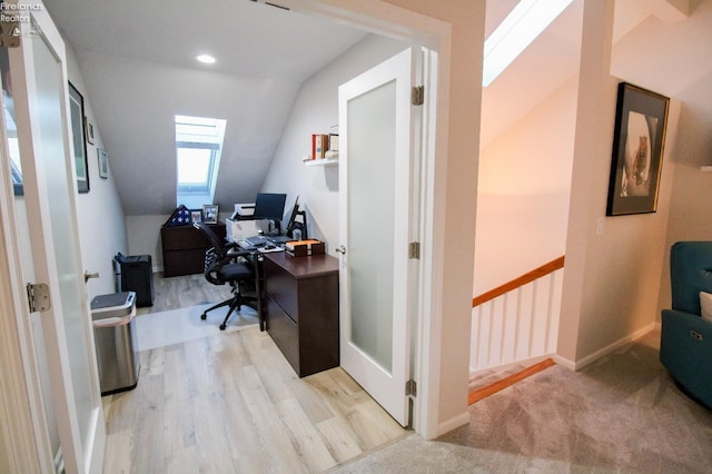 office space featuring lofted ceiling with skylight and light wood-type flooring