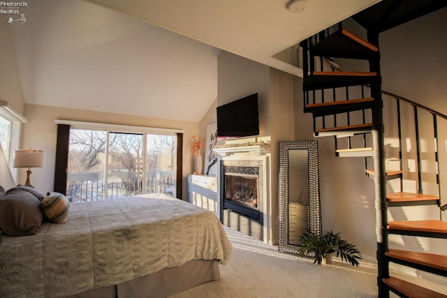 bedroom featuring lofted ceiling, access to exterior, carpet floors, and a tile fireplace