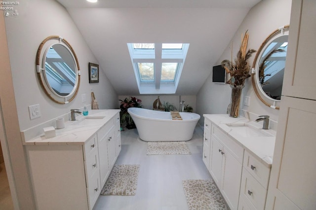 bathroom with a washtub, vanity, hardwood / wood-style flooring, and vaulted ceiling with skylight