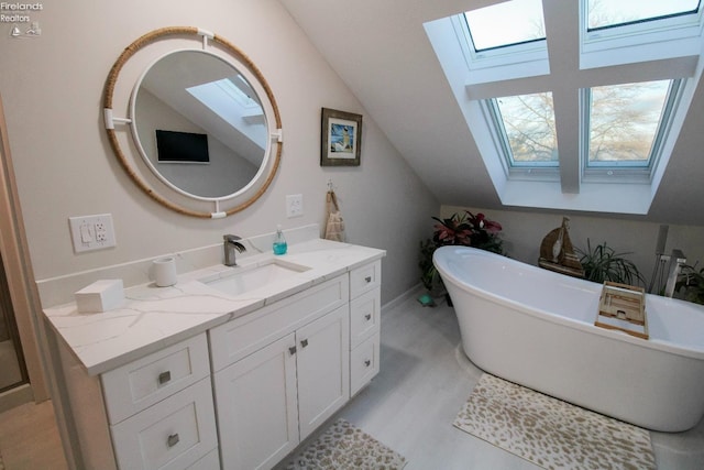 bathroom featuring vanity, wood-type flooring, lofted ceiling with skylight, and a bathtub