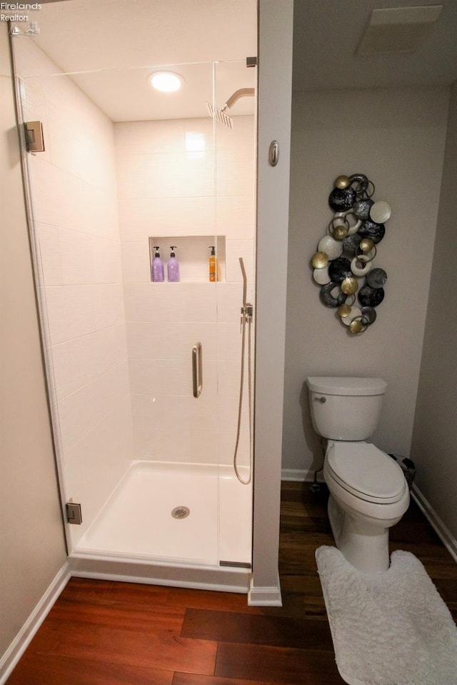 bathroom featuring hardwood / wood-style flooring, toilet, and a shower with door