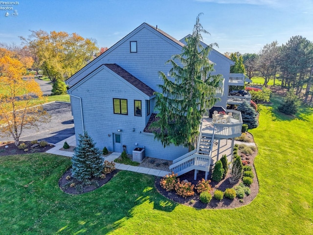 back of property featuring a wooden deck, a yard, and central AC