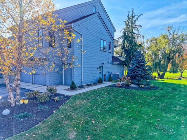 view of side of property with a garage, a yard, and central AC unit