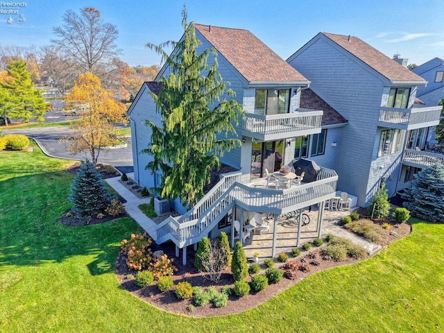 exterior space with a patio, a balcony, a deck, central air condition unit, and a front lawn