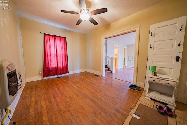 unfurnished living room featuring heating unit, hardwood / wood-style floors, a textured ceiling, and ceiling fan