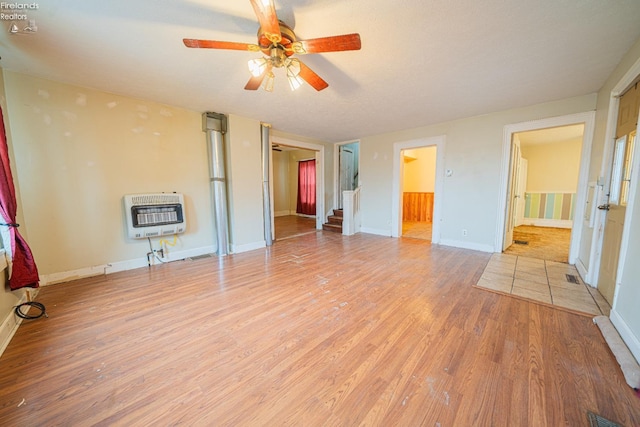 unfurnished bedroom featuring ceiling fan, connected bathroom, light hardwood / wood-style floors, and heating unit