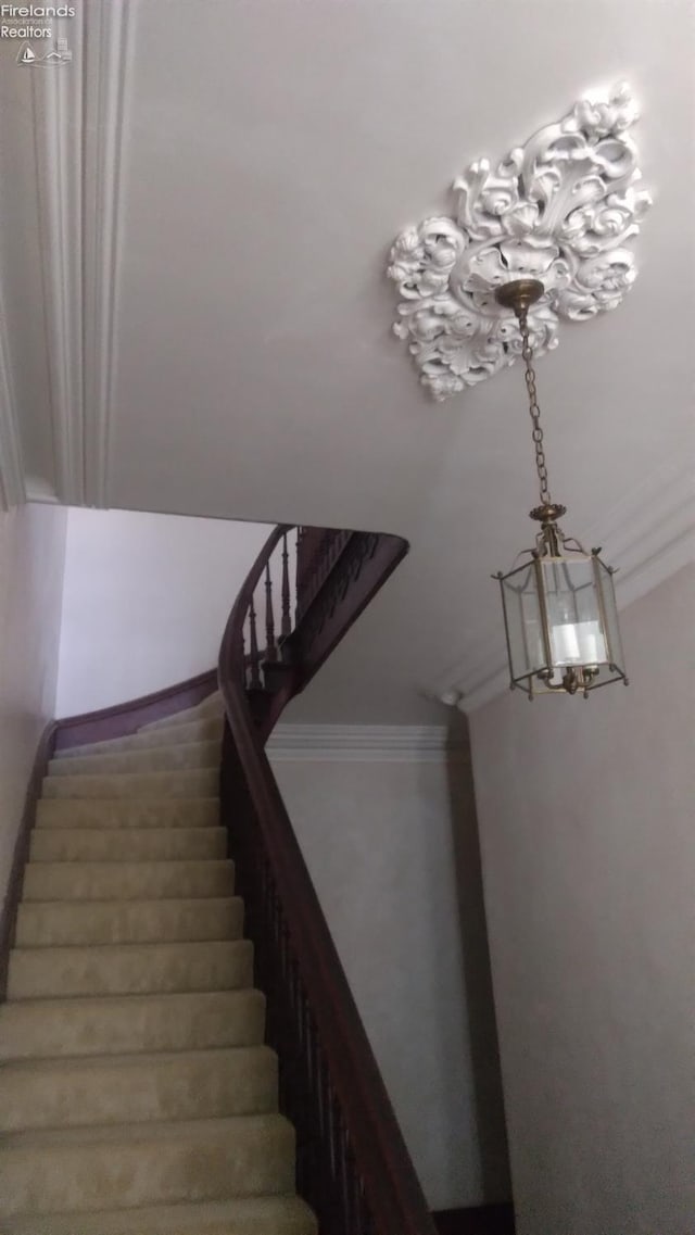 staircase featuring a notable chandelier and ornamental molding