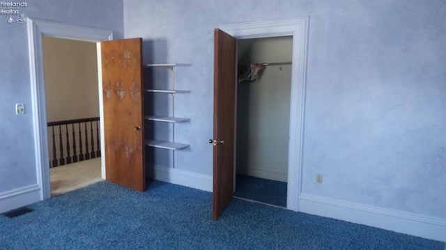 unfurnished bedroom with dark colored carpet and a closet