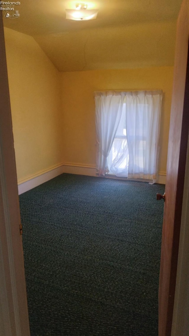 carpeted spare room with lofted ceiling