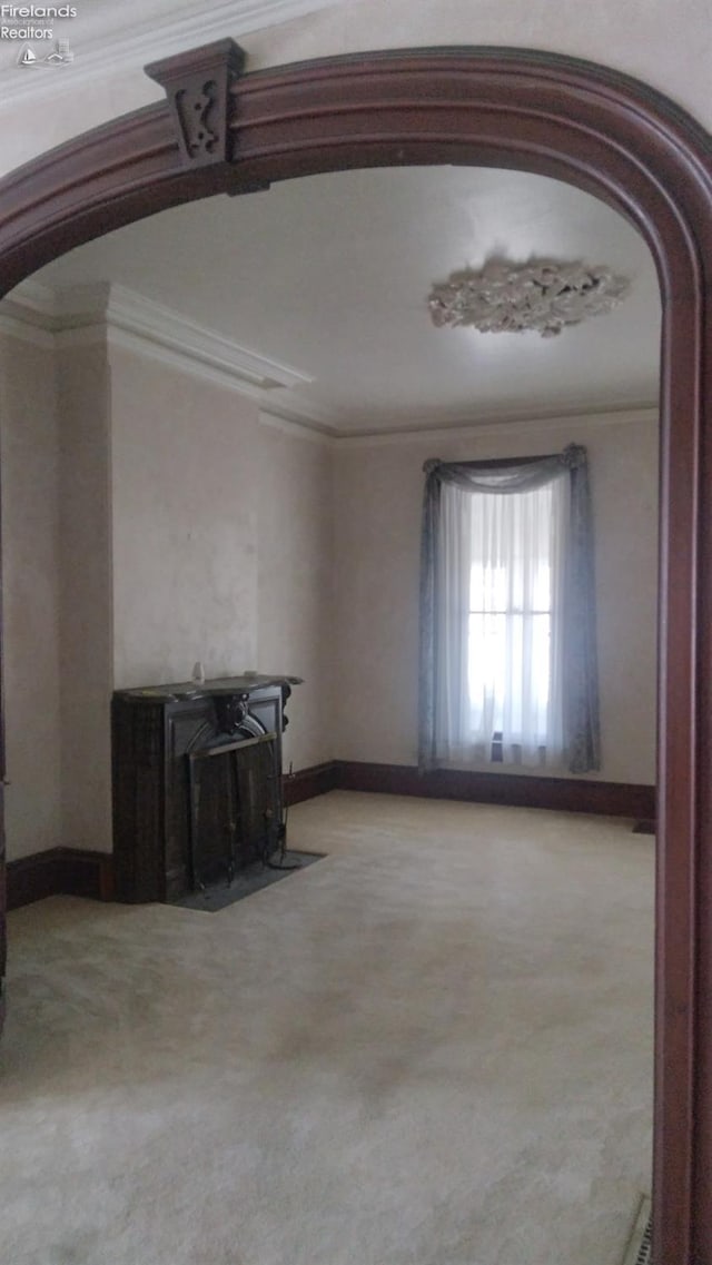 unfurnished living room featuring light colored carpet and ornamental molding