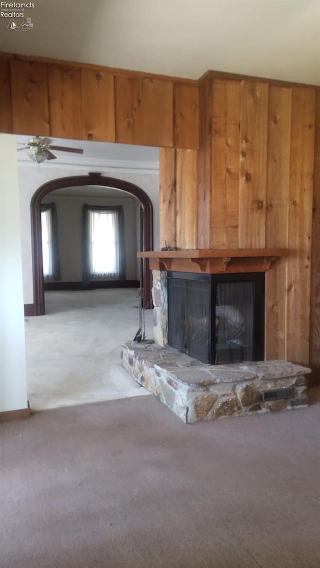 unfurnished living room with a stone fireplace and light carpet