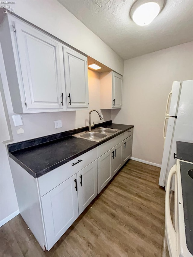 kitchen with white cabinetry, range, sink, and hardwood / wood-style floors