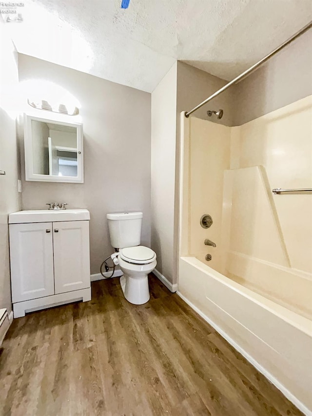 full bathroom with hardwood / wood-style floors, shower / bath combination, vanity, toilet, and a textured ceiling