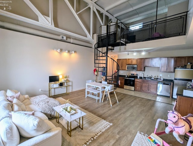 interior space with sink, a towering ceiling, light hardwood / wood-style flooring, and track lighting