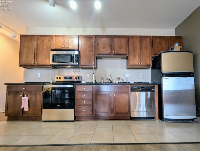 kitchen featuring stainless steel appliances, sink, light tile patterned floors, and track lighting