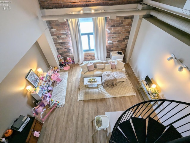 living room featuring brick wall and wood-type flooring